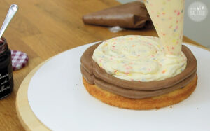 Konfetti Drip Cake: Die Konfetticreme auf dem Tortenboden verteilen