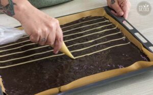 Black & White Wickeltorte Rezept: Dünne Streifen auf dunklen Biskuit spritzen